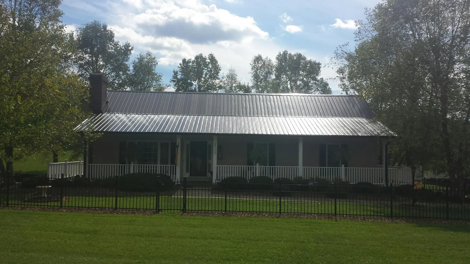 Gray metal roof on a brick ranch with a full width front porch — Gutter Guard Installation work by our crew in Ionia